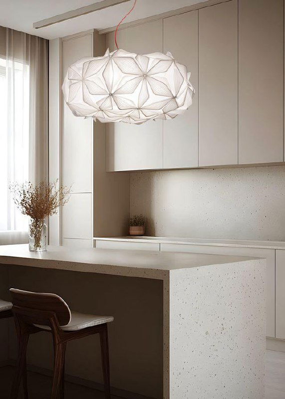 Подвесной светильник C’est La Vie над кухонной зоной: крупный план белой цветочной структуры на фоне светлой минималистичной кухни и барного острова.