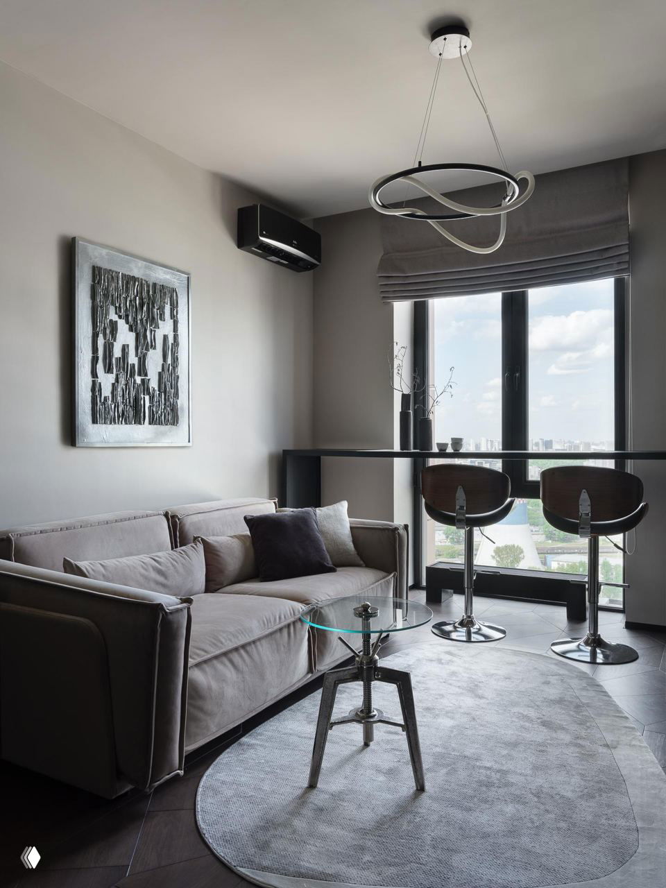 Угол гостиной с диваном, большие окна и барная стойка с двумя барными стульями — сочетание минималистичных форм и мягких текстур на фоне города.