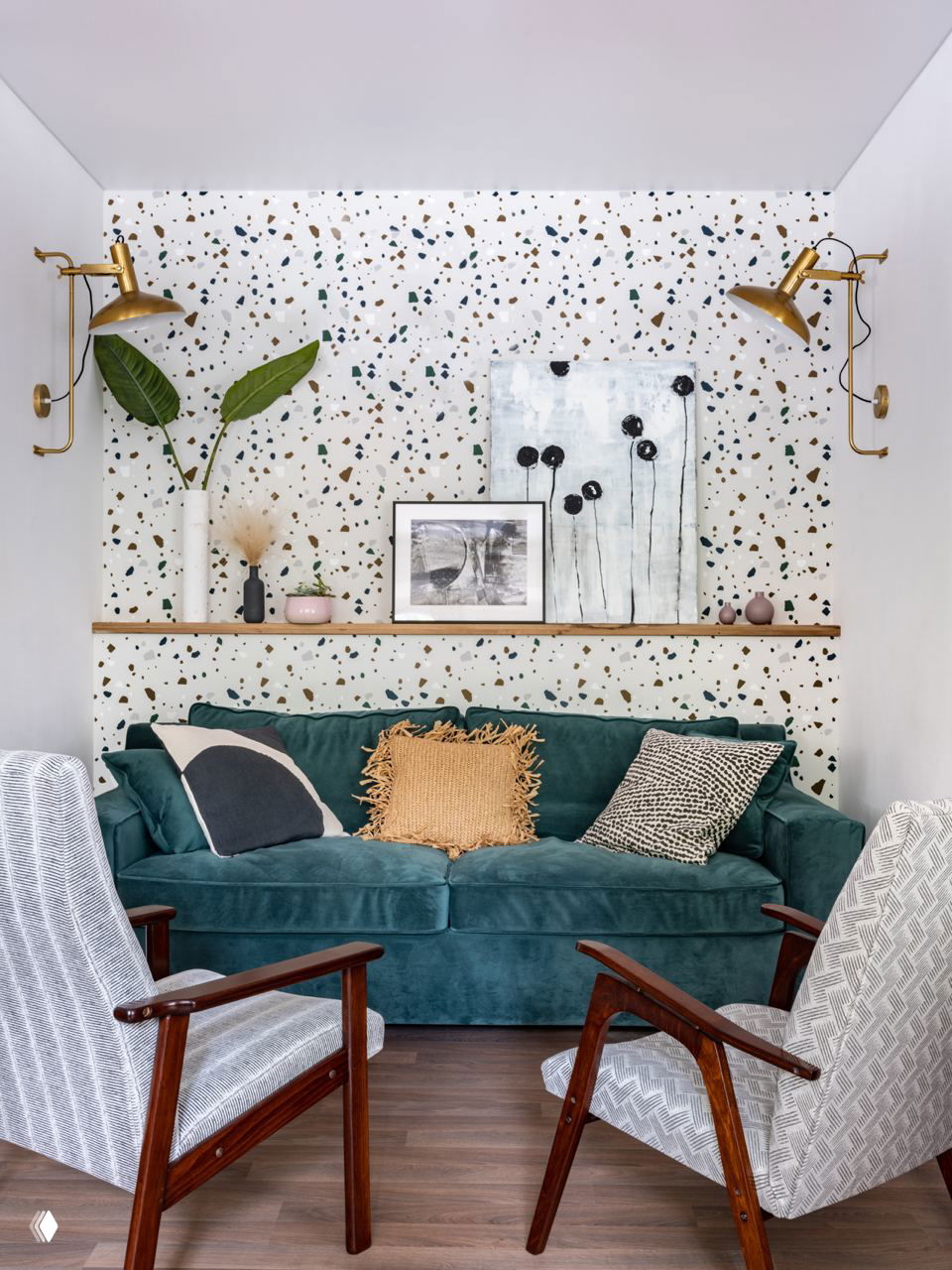 Гостиная с терраццо-обоями на заднем плане, бирюзовый диван и декоративные подушки, настенные светильники и полка с картинами — пример текстурного и цветового акцента в маленькой комнате.