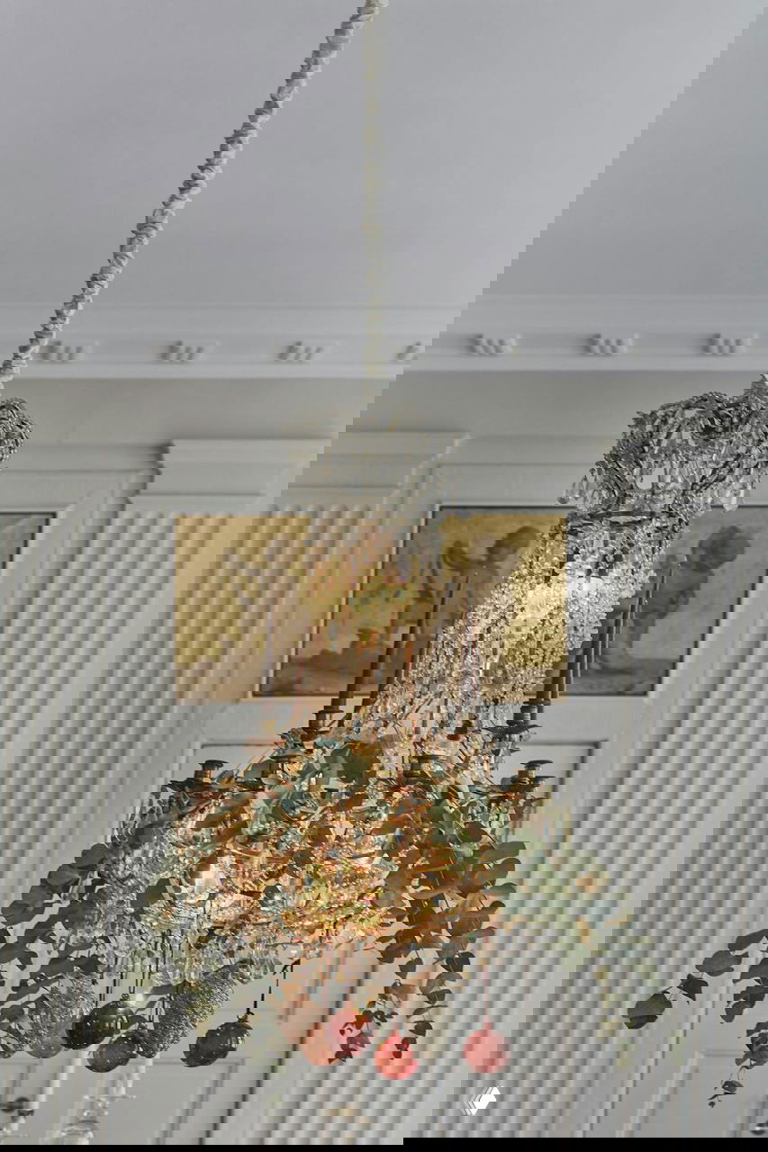 Интерьерный натюрморт: массивный деревянный стол, холст на мольберте с портретом, зажженные свечи и золотые праздничные шары.