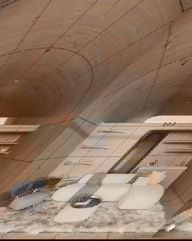 Интерьер AltiHut: обшитые натуральным деревом сводчатые стены, компактная гостиная с мягкой мебелью и встроенной мини-кухней.