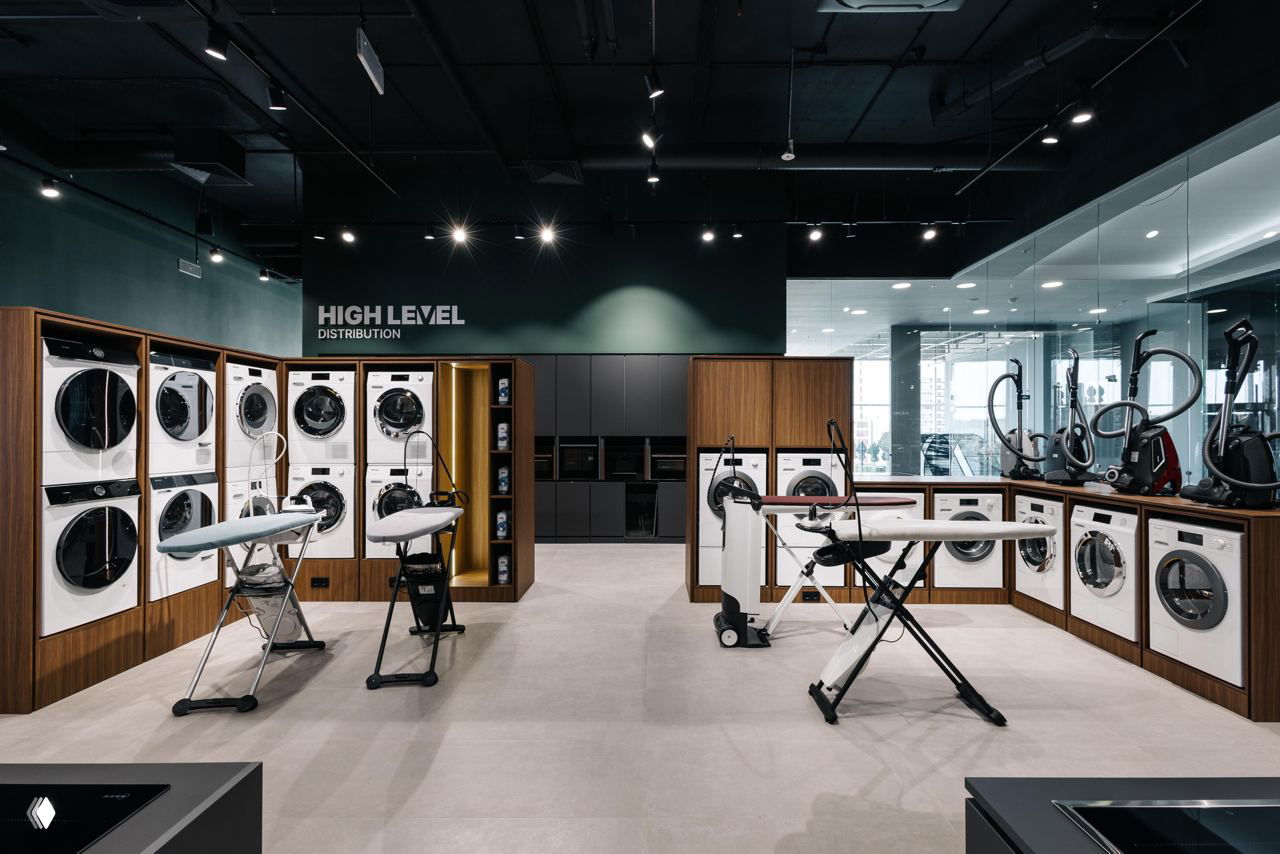 Выставочная зона бытовой техники в шоуруме High Level: ряд стиральных машин, гладильные станции и демонстрационные стенды для презентаций и обучения дизайнеров.