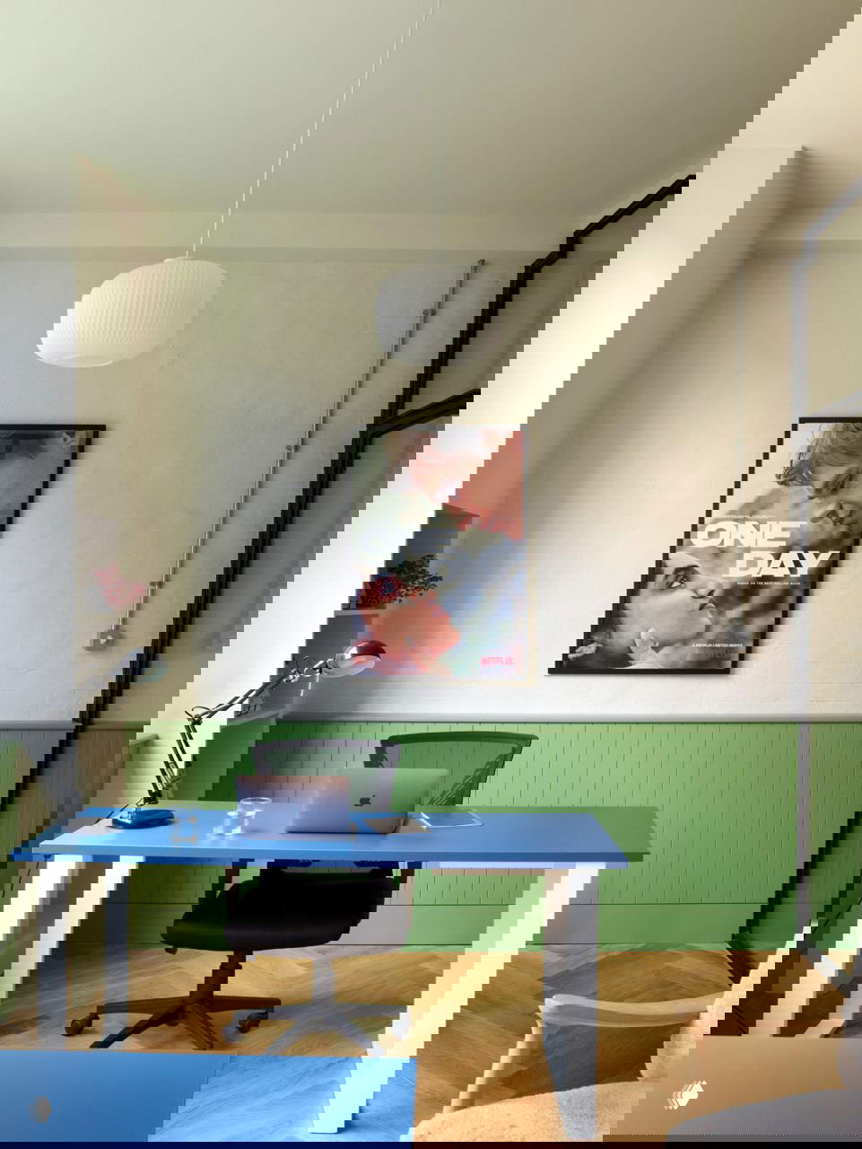 Рабочее пространство с ярко-синим столом, постером «ONE DAY» на стене, зелёной нижней панелью и ноутбуком — сочетание цвета и функциональности.