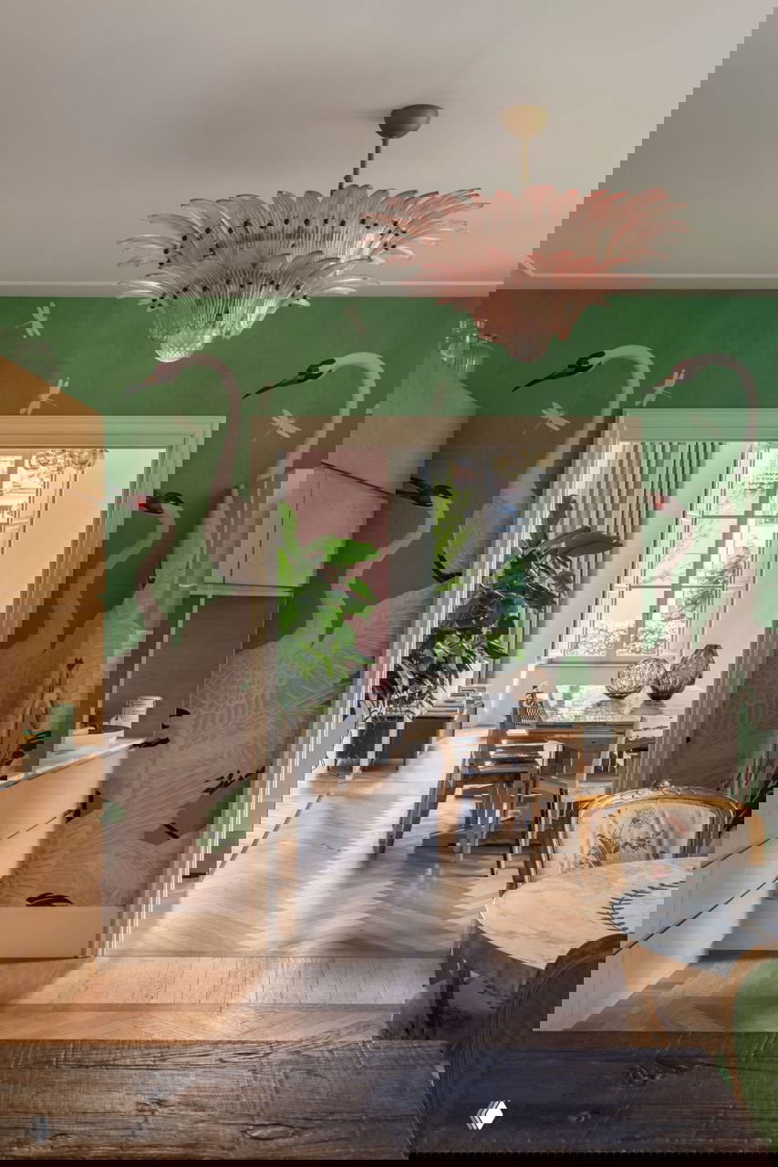 Кухонная ниша с крупными обоями Gucci: бело-розовые журавли на светло-зелёном фоне, в комнате видна розовая муранская люстра.