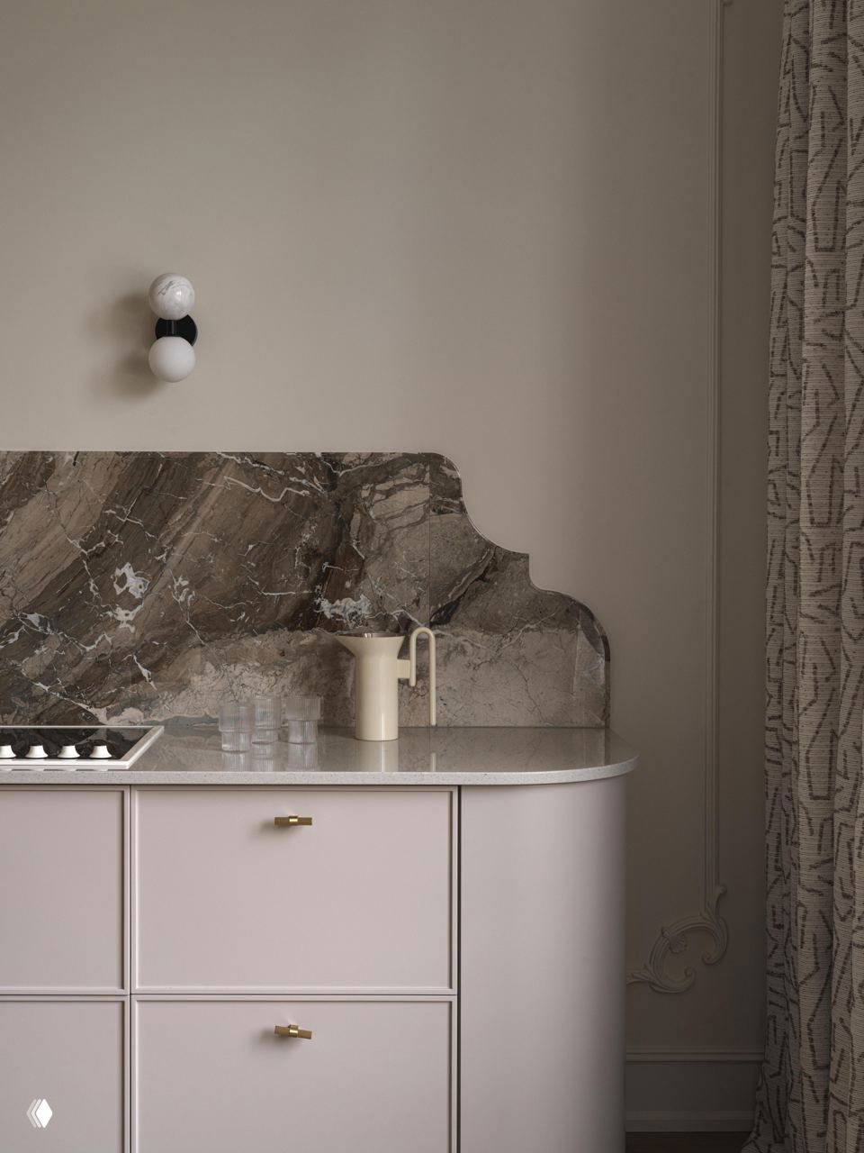 Фрагмент кухни: закруглённые фасады светлого тона, мраморный фартук с округлым краем и минималистичный декор в атмосферном бежевом интерьере.