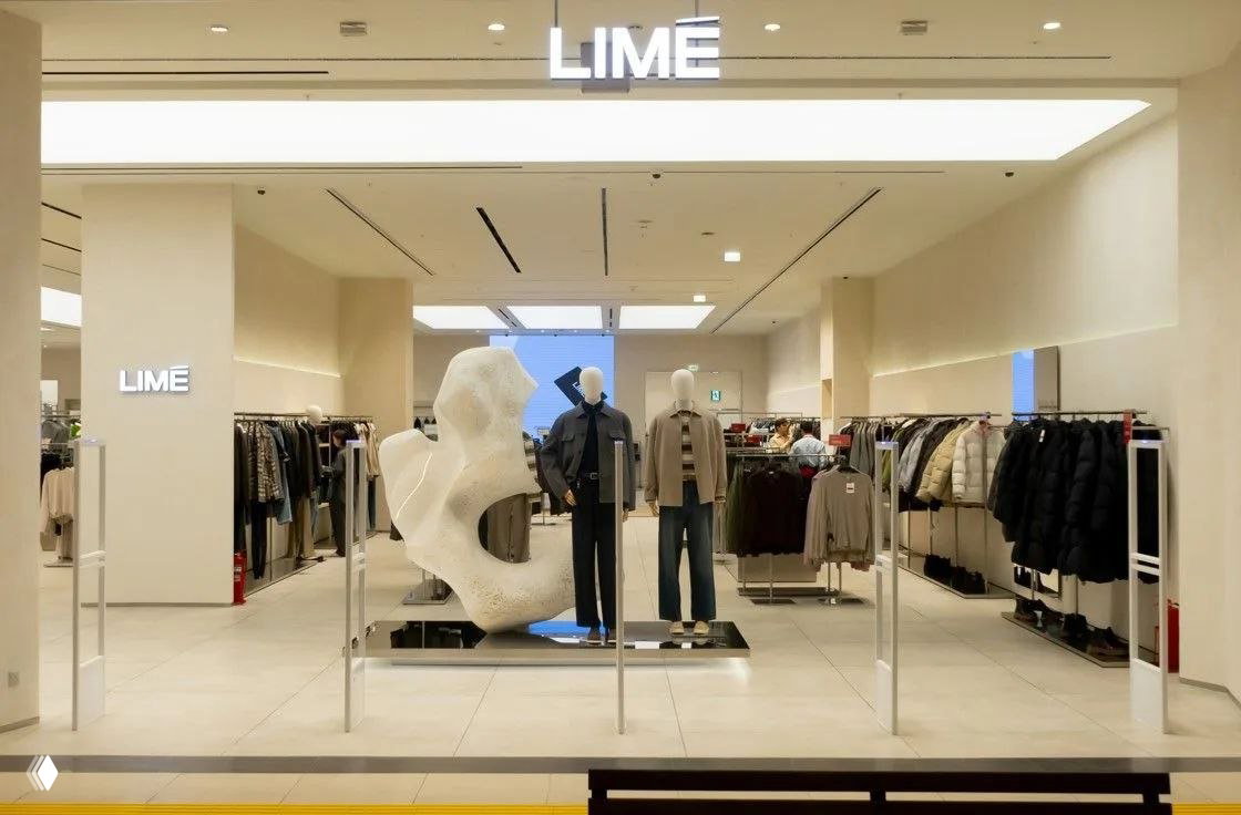 Входная зона магазина LIME с подсветкой вывески, скульптурной инсталляцией и выдержанным освещением, подчёркивающим витрину и композицию