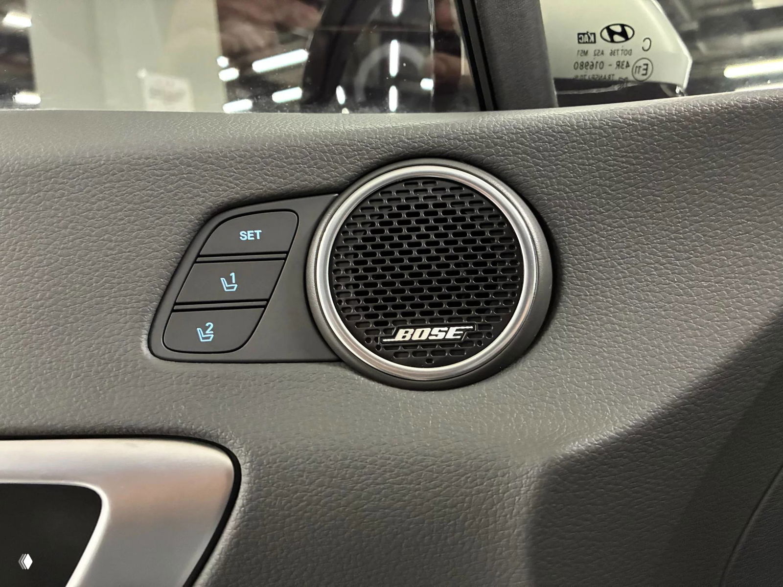 Фрагмент дверной обивки с динамиком Bose и кнопками памяти сидений (SET, 1, 2) в интерьере Hyundai Sonata, крупный детализированный план.