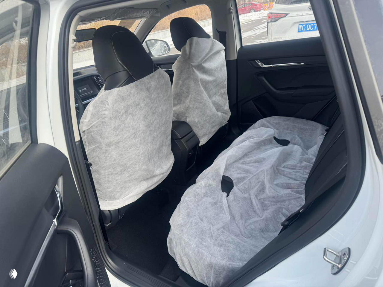 Вид на задний ряд сидений Skoda Kamiq: сиденья и пол покрыты одноразовыми чехлами, интерьер в заводском состоянии перед экспортом.