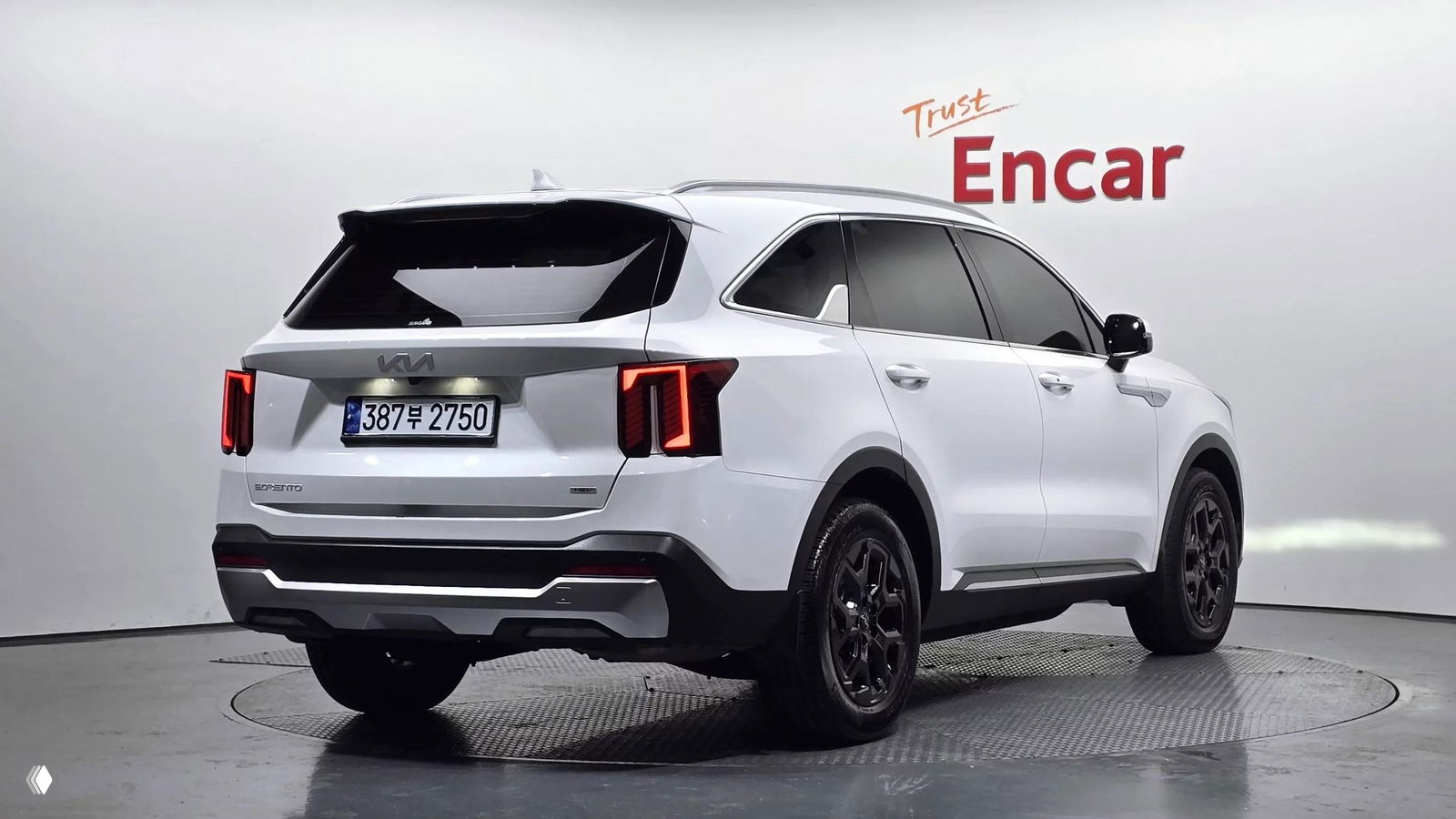 KIA Sorento 2024 белого цвета, вид сзади и в три четверти, заметны задние фонари, шильдик производителя и корейский номерной знак.