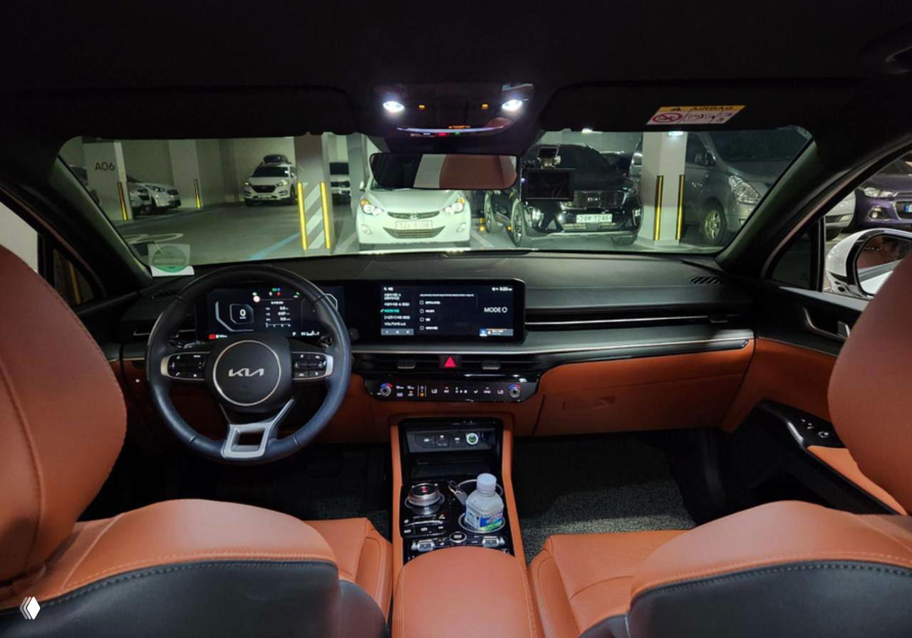 Снимок салона KIA K5: панель приборов, большой мультимедиа экран и руль; интерьер показан для оценки комплектации и состояния перед отправкой.