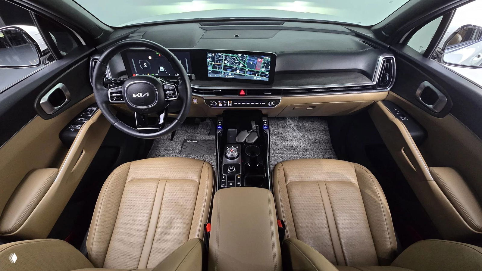 Салон KIA Sorento 2024: передние сиденья бежевого тона, центральная консоль с декоративными вставками и экран мультимедиа в профиль.