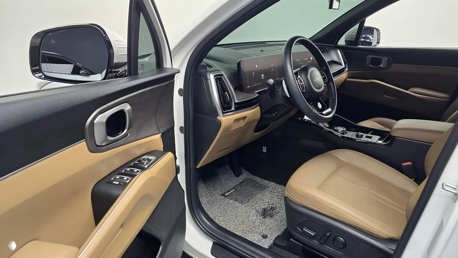 Открытая передняя дверь и вид на водительское место KIA Sorento 2024, видны сиденье, дверная карта и зеркала, общий интерьерный ракурс.