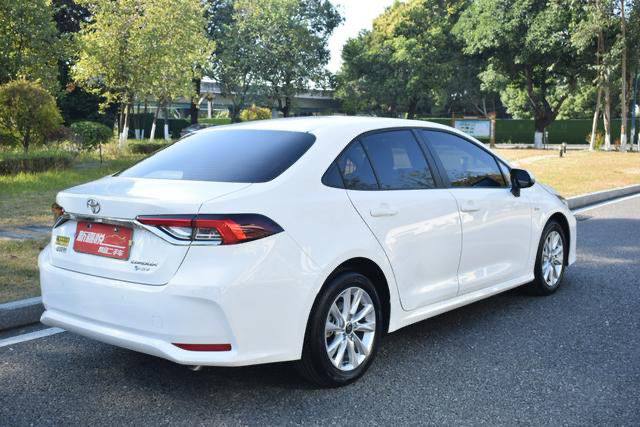 Toyota Corolla Hybrid 2025 белого цвета, вид сзади: багажник и фонари на парковке, автомобиль без заметных повреждений.