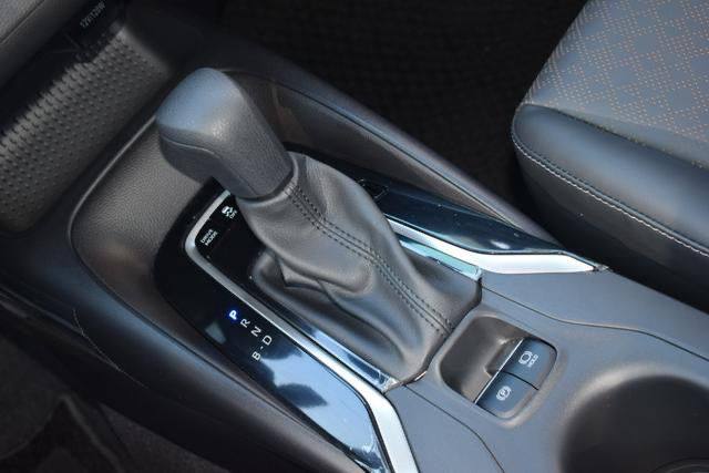 Центральный тоннель Toyota Corolla Hybrid: селектор коробки передач АКПП, кнопки управления и отделка вблизи рычага переключения.