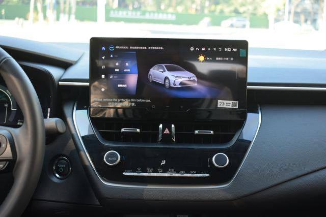 Мультимедийный экран Toyota Corolla Hybrid 2025: интерфейс на дисплее, элементы управления климат-контролем и центральная консоль.