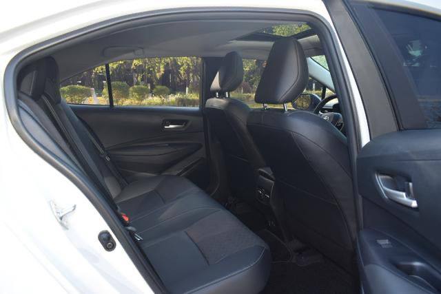 Задние сиденья Toyota Corolla Hybrid 2025: свободное пространство для ног, чистые обивки и вид на передние кресла со стороны двери.