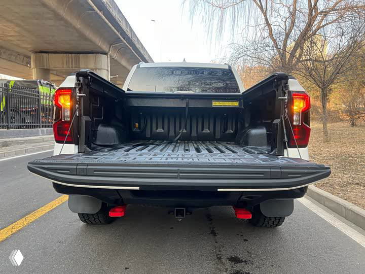 Грузовая платформа пикапа Ford Ranger с открытым задним бортом, пластиковая защита днища кузова и видимая поверхность кровати для перевозки груза, стоящий на дороге.