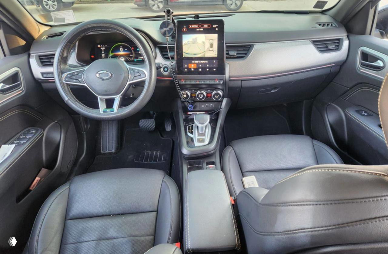 Салон автомобиля с вертикальным сенсорным экраном на центральной консоли, вид на рулевую колонку и элементы управления мультимедиа.