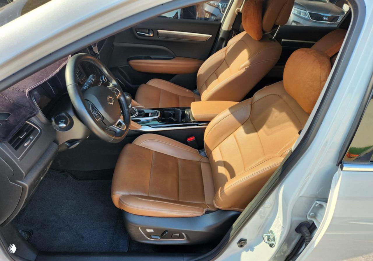 Фотография салона с коричневыми кожаными сиденьями, вид на передние кресла и центральный тоннель, подчёркнуты материалы отделки.