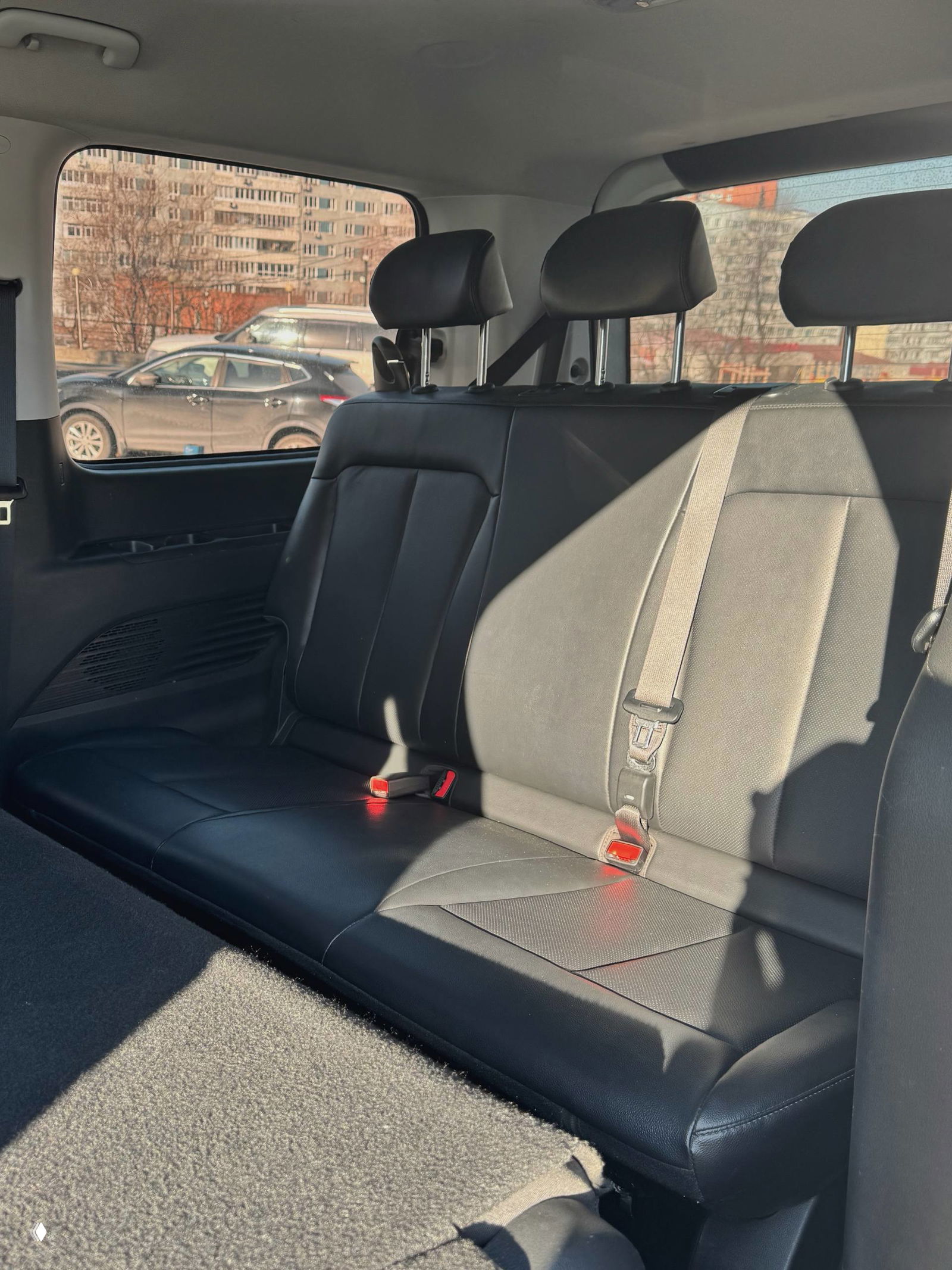 Другой ракурс задних сидений Hyundai Staria с подчёркнутой обшивкой и ремнями безопасности, вид на багажное пространство и боковое окно.