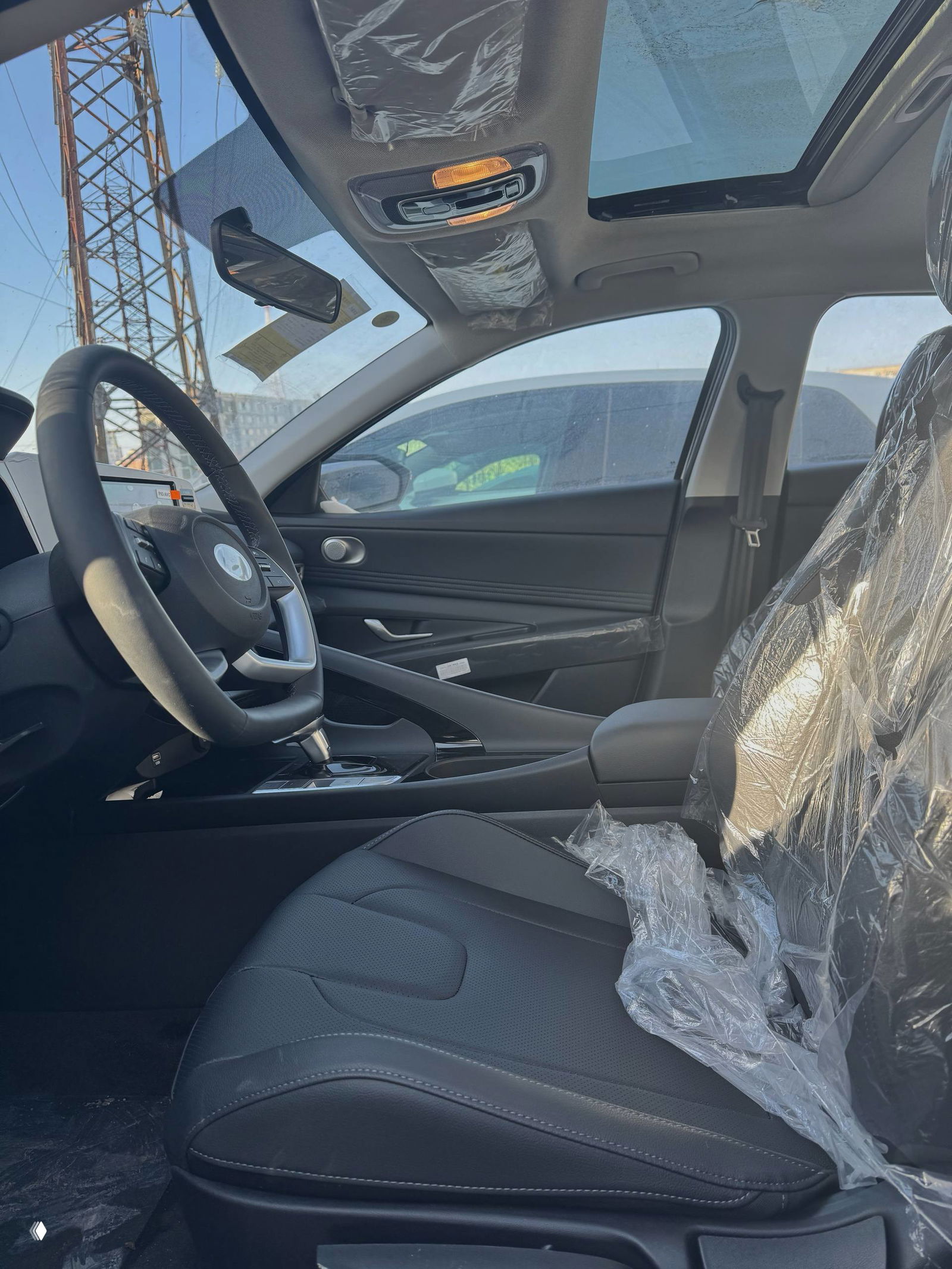 Вид салона сверху с панорамной крышей (люком), защитной плёнкой на передних сиденьях и центральной консолью — новая комплектация автомобиля.