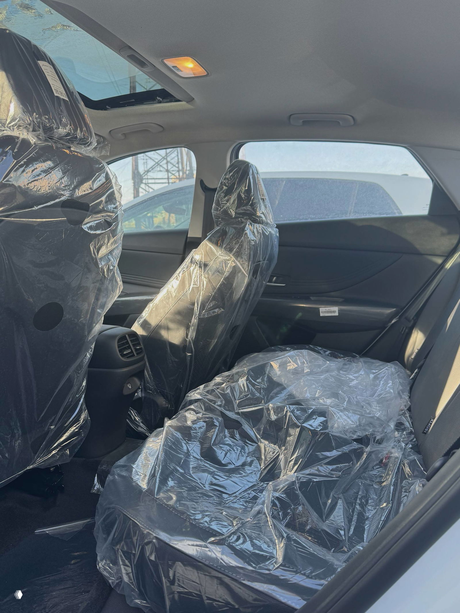 Задние сиденья Hyundai Elantra упакованы в заводскую плёнку, вид пространства для пассажиров и вентиляционные дефлекторы задней части консоли.