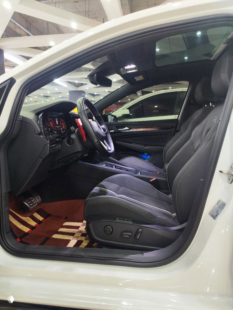 Водительское сиденье и передняя часть салона Volkswagen Golf R‑Line, вид через открытую дверь с видимыми регулировками сиденья