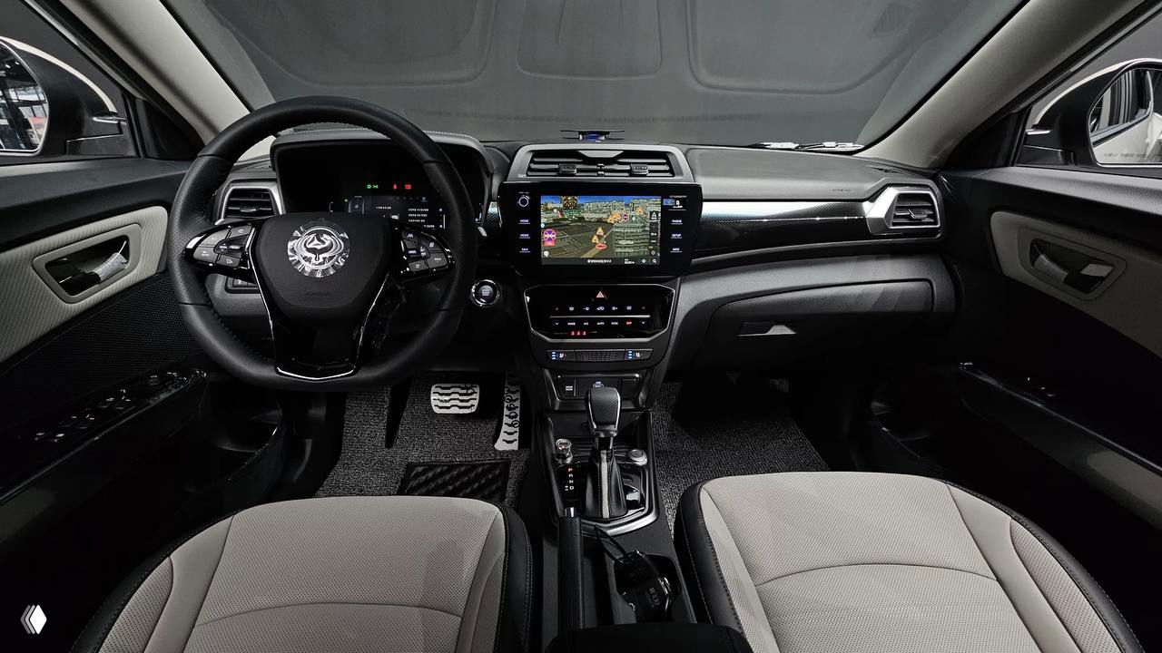 Фото салона SsangYong Tivoli 2026 — общий вид передней части салона, приборной панели, экран мультимедиа и передние сиденья в светлой отделке.
