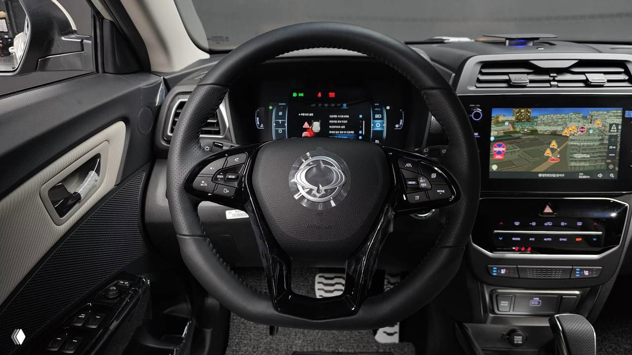 Фотография рулевой колонки и панели приборов SsangYong Tivoli 2026, видно кнопки на руле, индикаторы на цифровой панели и центральный экран.