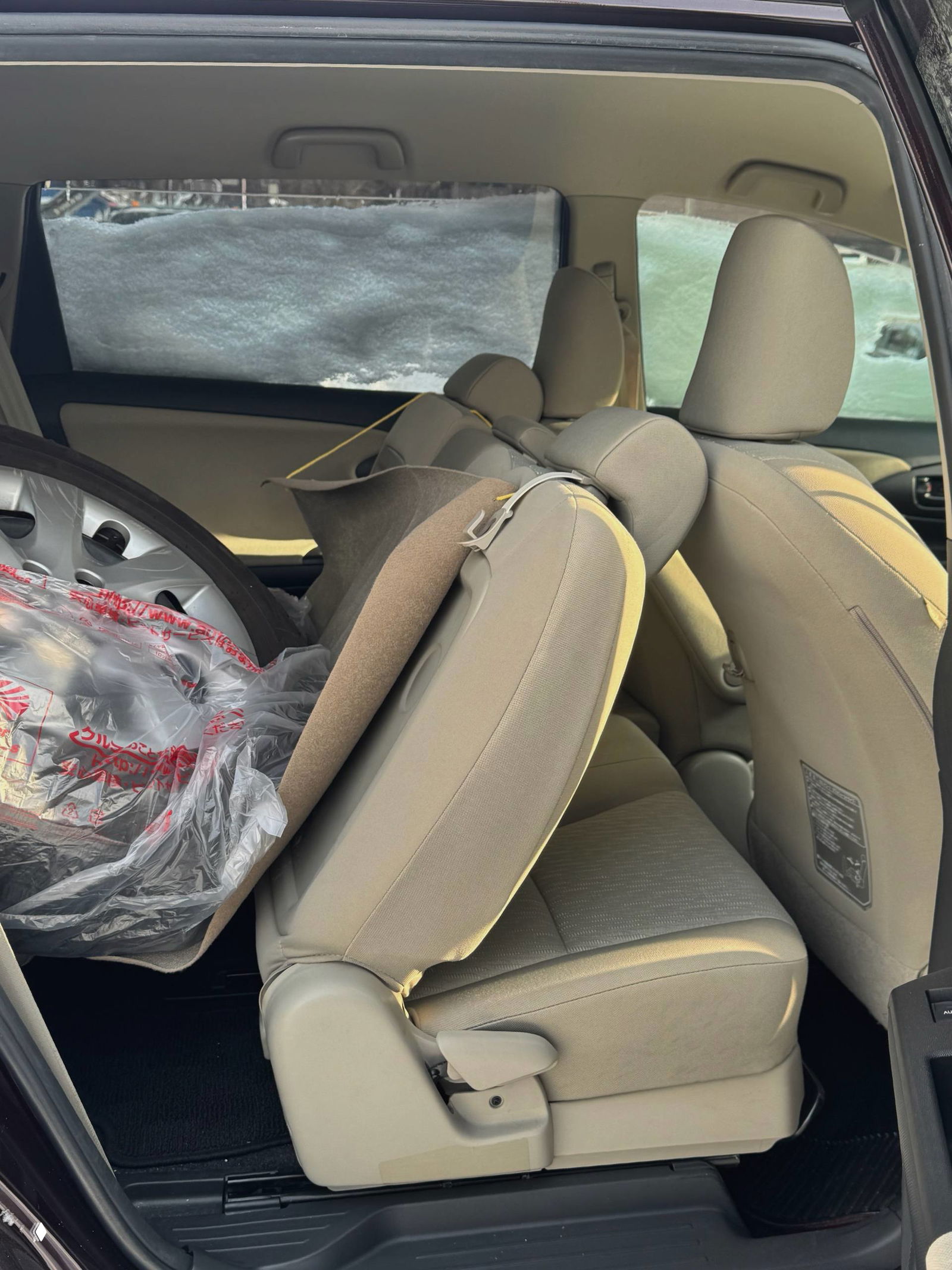 Задние сиденья Toyota Wish сложены, виден багажник с упакованным комплектом зимних колёс — состояние обивки и складывания сидений.