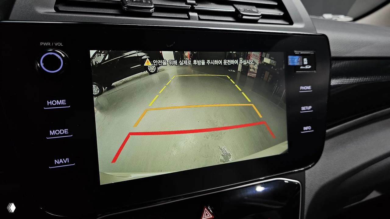 Крупный план изображения с камеры заднего вида на экране мультимедиа SsangYong Tivoli 2026, видны контрольные линии парковки и предупреждающие пиктограммы.