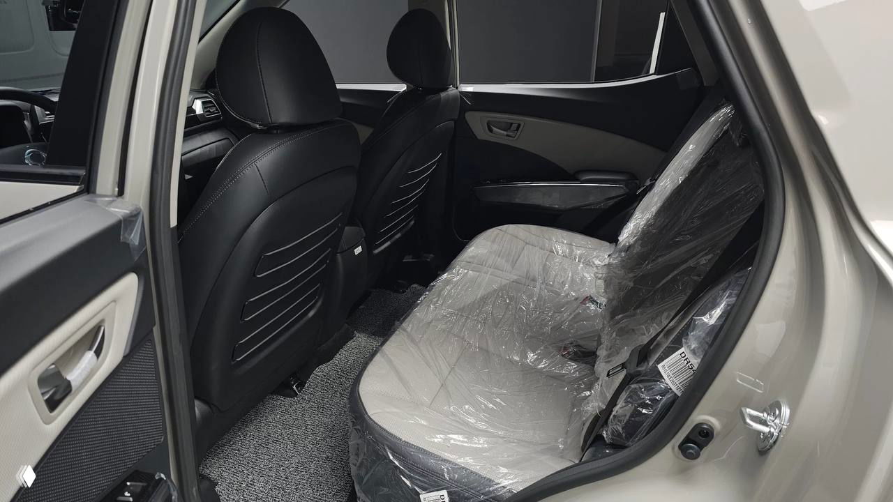 Фотография заднего пассажирского ряда SsangYong Tivoli 2026 с защитной плёнкой на сиденьях и светлой обивкой, видно пространство для ног и состояние салона.