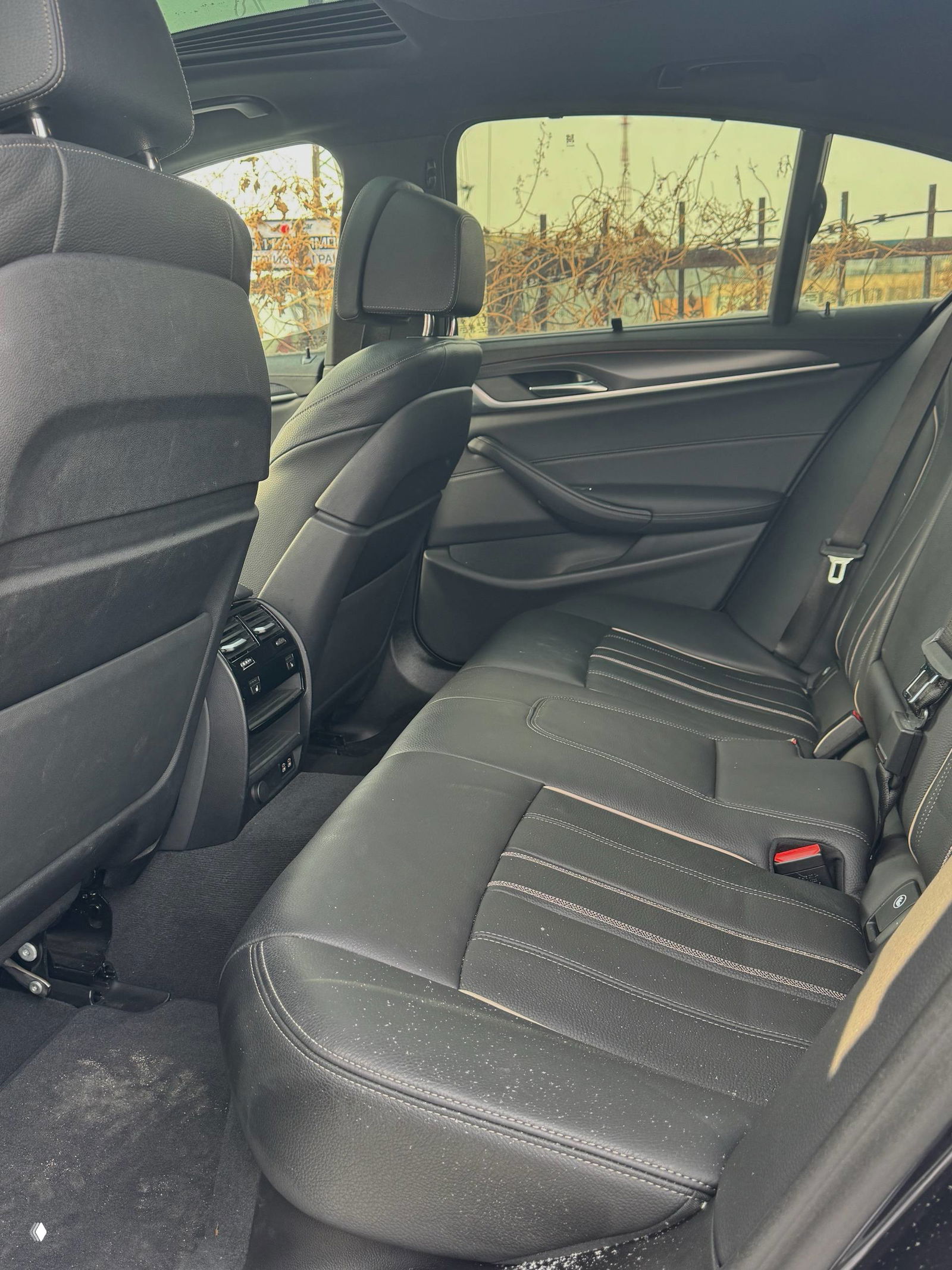 Задние сиденья BMW 520i: пространство для пассажиров, кожаная обивка и воздуховоды с подогревом для заднего ряда, показан общий вид задней зоны салона.