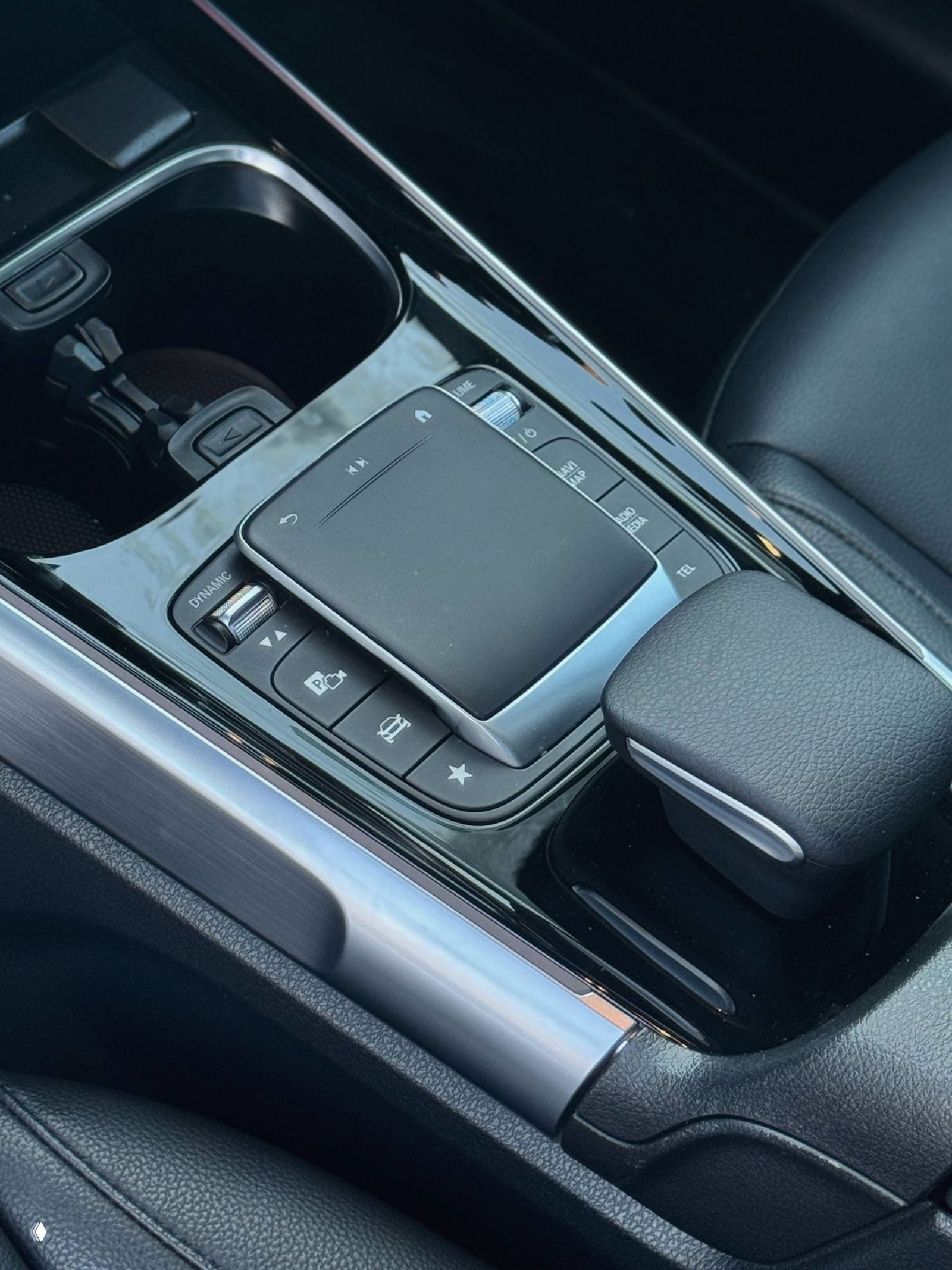 Центральная консоль Mercedes GLB — крупный план тачпада управления, хромированные детали и чёрная глянцевая отделка вокруг селектора передач.