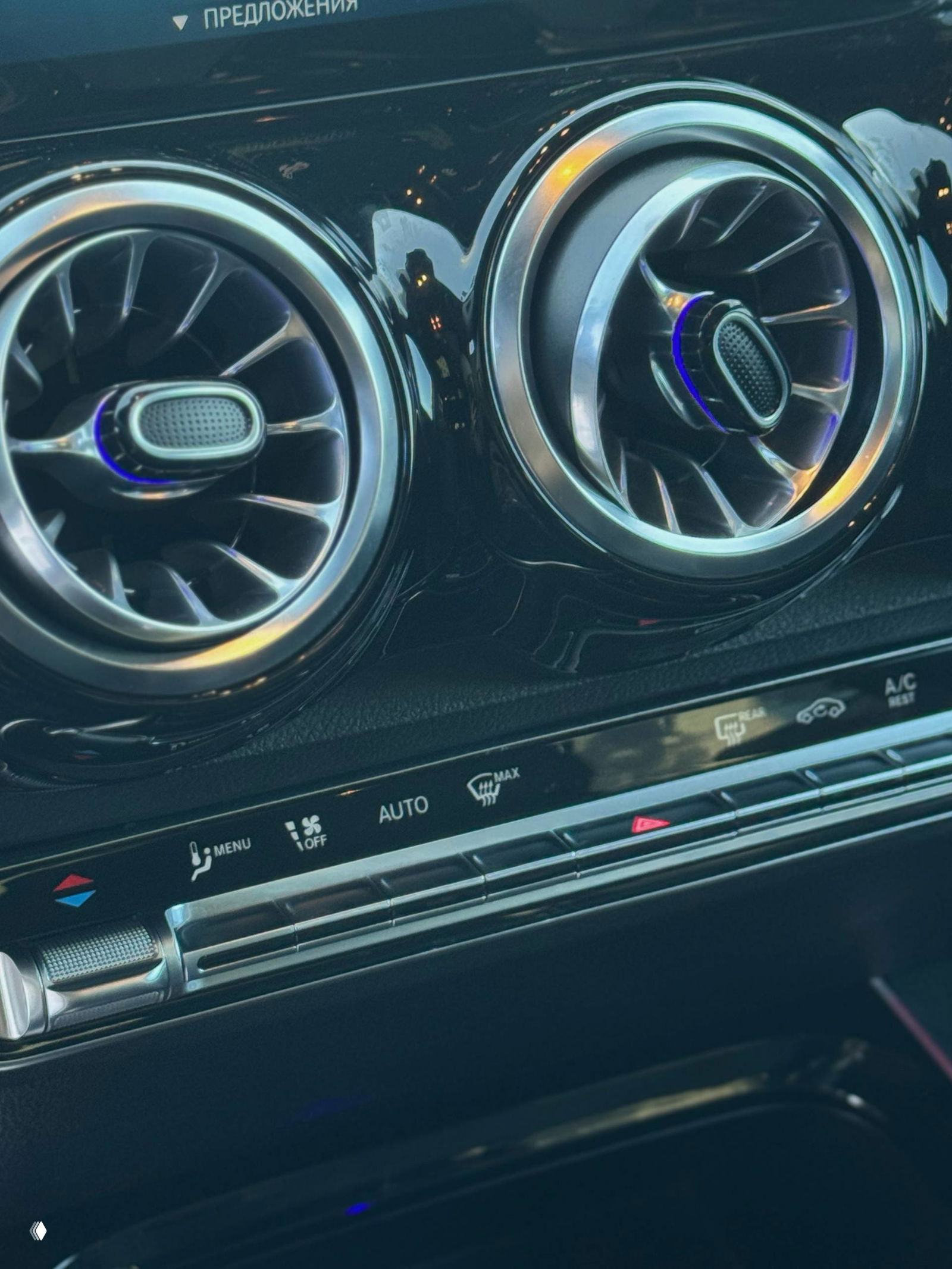 Крупный план круглых воздуховодов передней панели Mercedes с декоративной подсветкой и панелью климат-контроля снизу, хромированные элементы.
