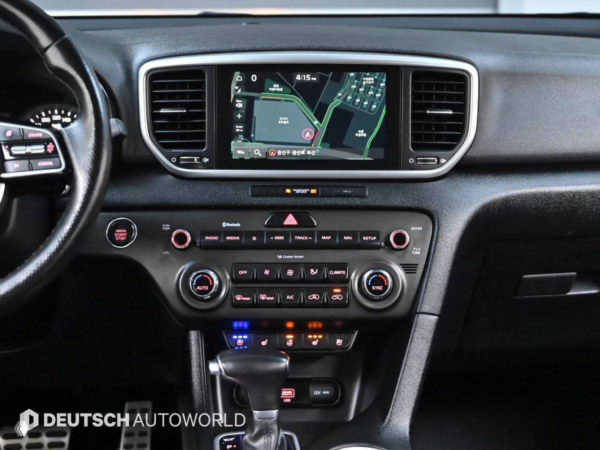 Интерьер KIA Sportage: приборная панель и центральная консоль с экраном навигации, климат-контролем и рычагом переключения передач.