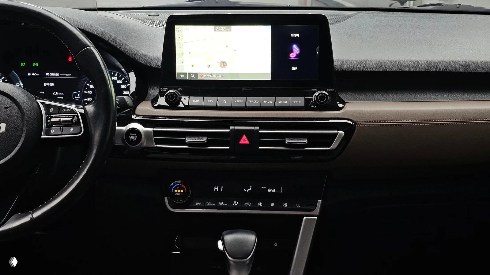 Передняя панель и мультимедиа KIA Seltos: центральный дисплей, орган управления климатом и блок кнопок под экраном на коричневой отделке торпедо.