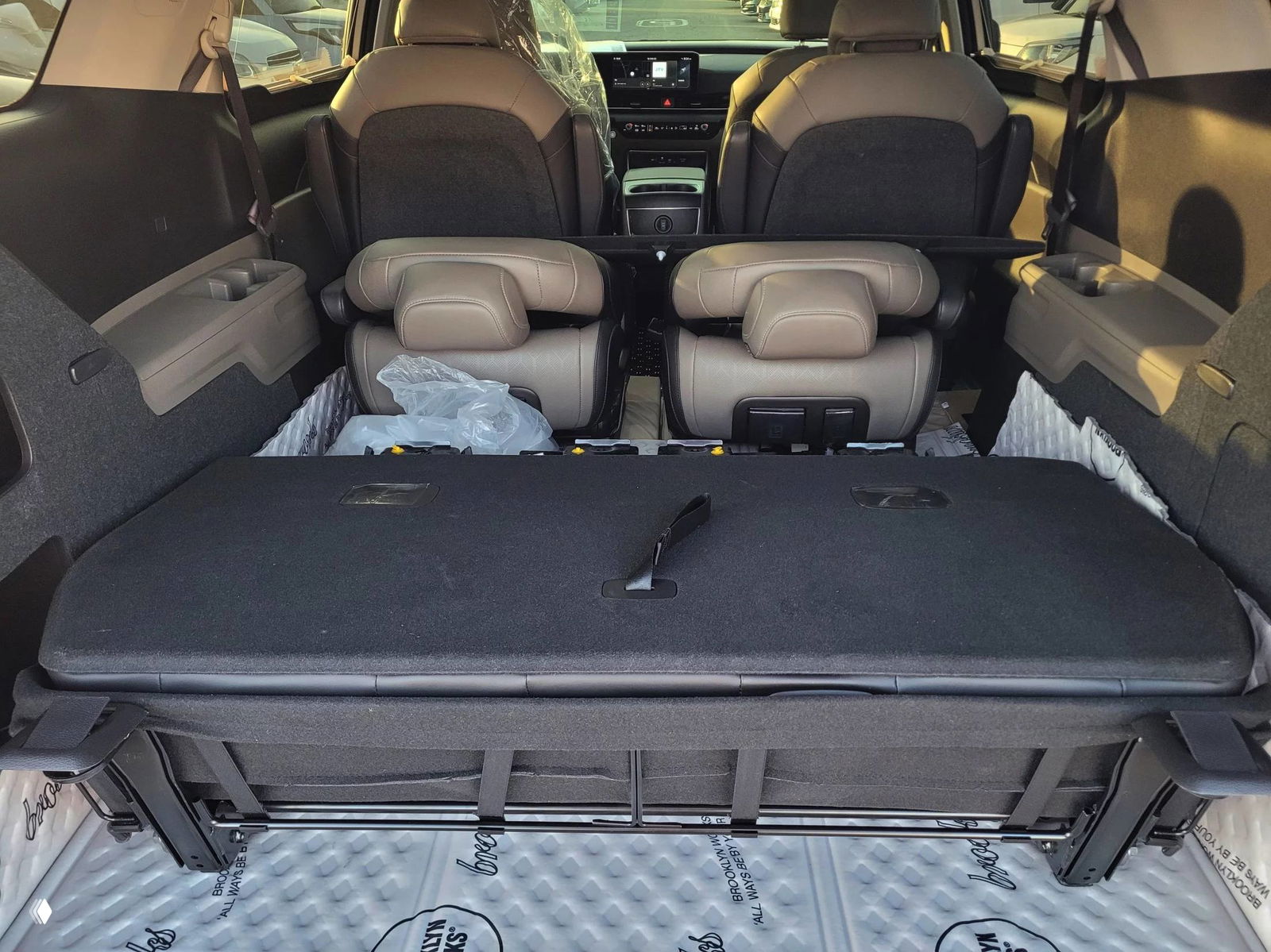 Багажное отделение KIA Carnival с разложенными сиденьями и ровной погрузочной площадкой, показана практичность трансформации салона для груза или отдыха.