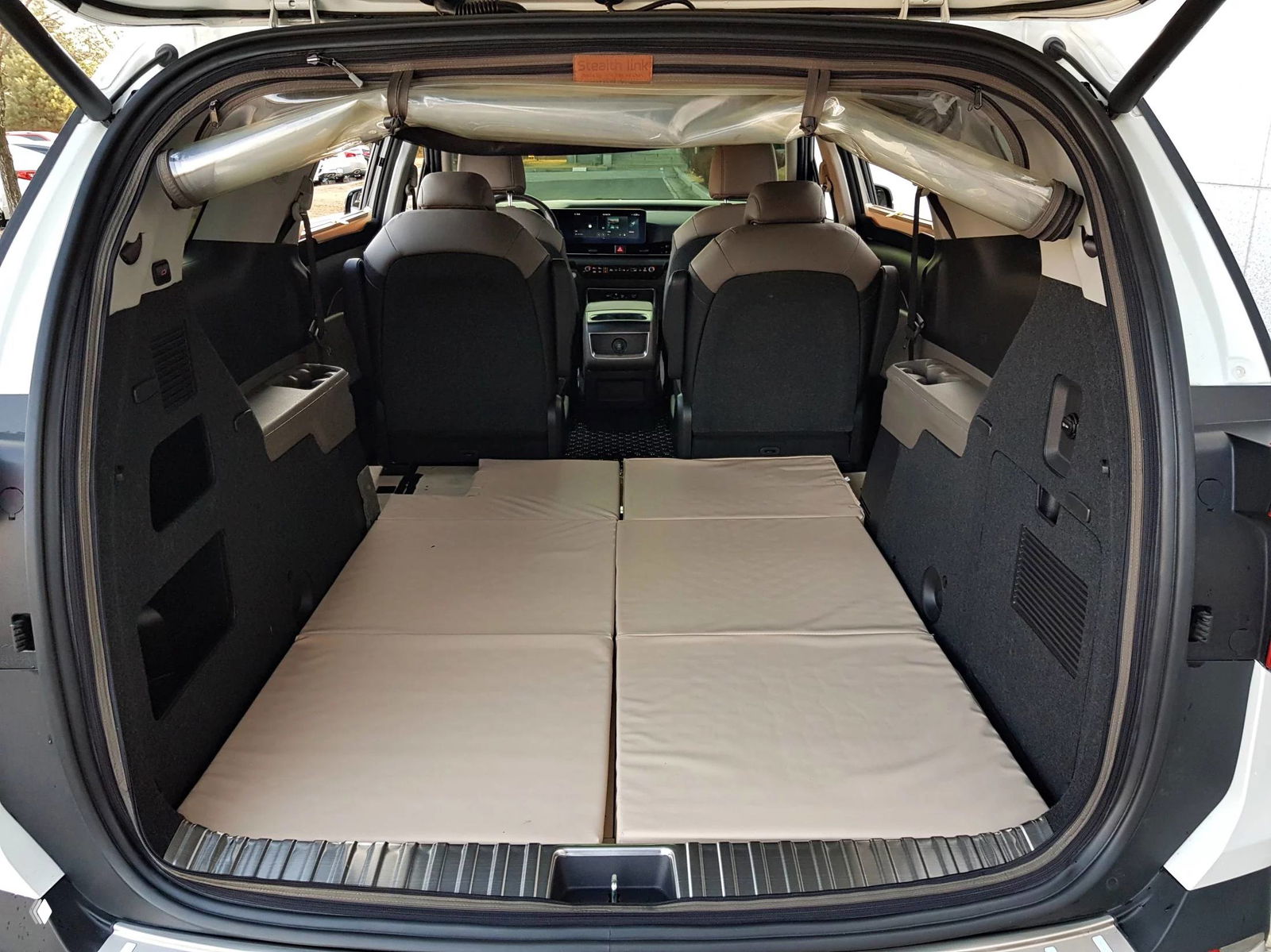 Вид в глубину багажника KIA Carnival с откинутыми задними сиденьями и ровным пространством для перевозки крупногабаритных предметов.