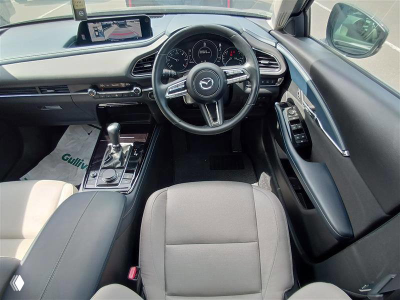 Интерьер Mazda CX-30 2023 — вид на переднюю панель и рулевое управление, салон светлый, на сиденьях нет явных следов износа.