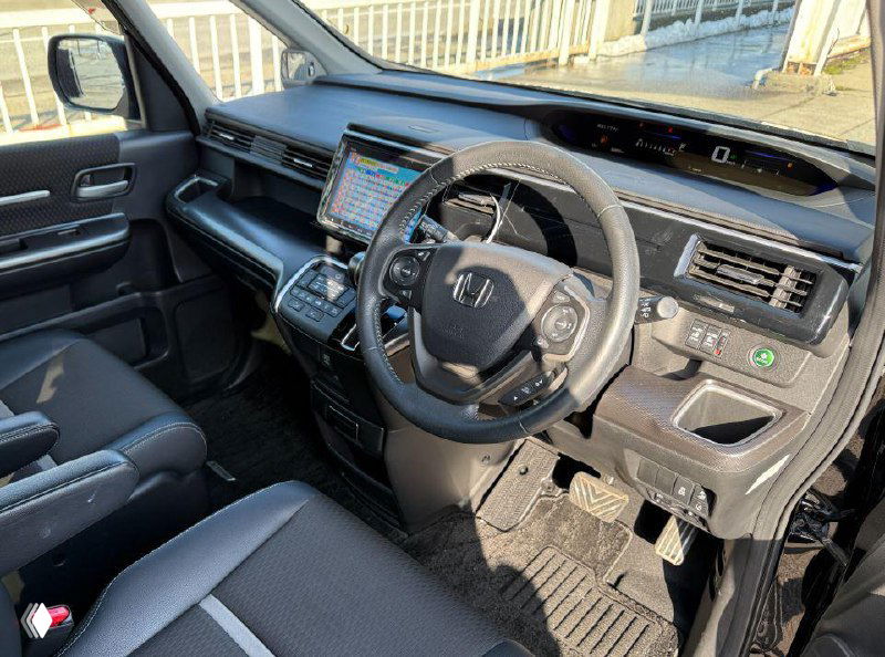 Фотография салона Honda Stepwgn с видом панели и руля; изображение частично искажено цифровыми артефактами и шумами.