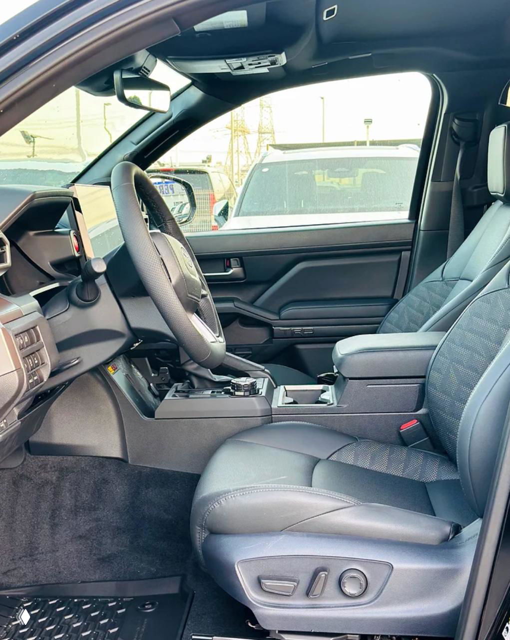 Переднее пассажирское место Toyota Tacoma: кожаное сиденье, регулировки, центральный подлокотник и элементы управления на дверной панели.