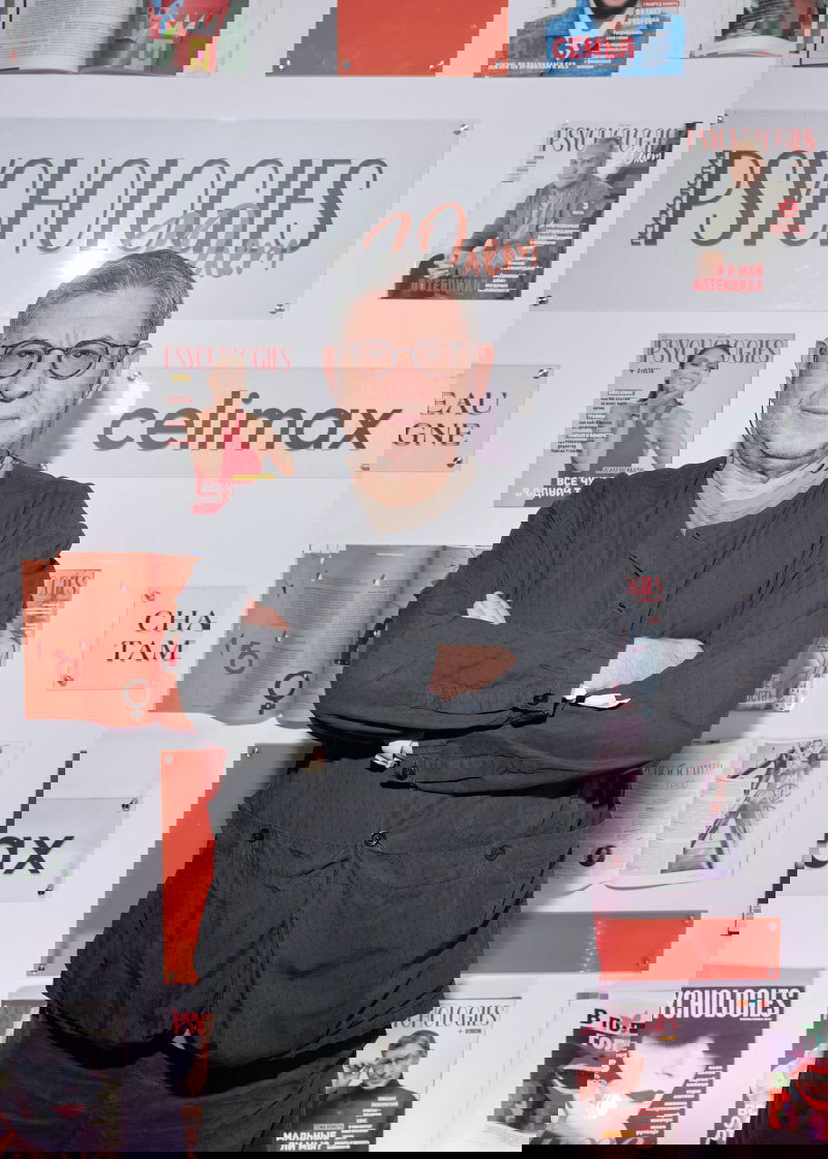 Портретный снимок гостя на фоне брендволла PSYCHOLOGIES: спокойная поза, очки, крупный план на фоне обложек и логотипов.