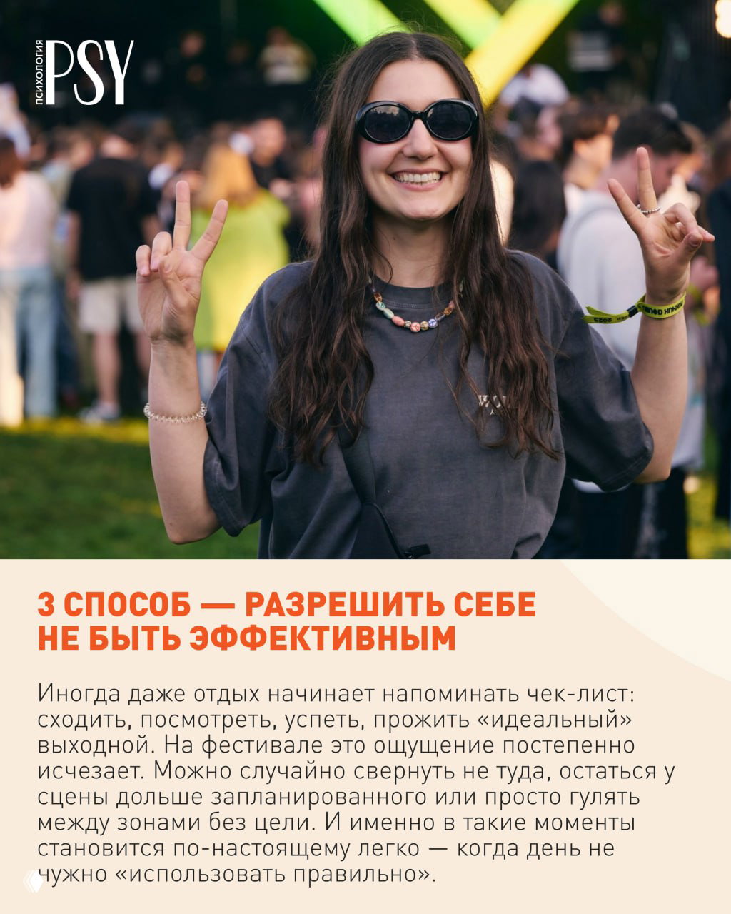 Улыбающаяся женщина в солнцезащитных очках показывает знак мира на фоне фестивальной толпы и сцены, кадр передаёт лёгкость и радость.