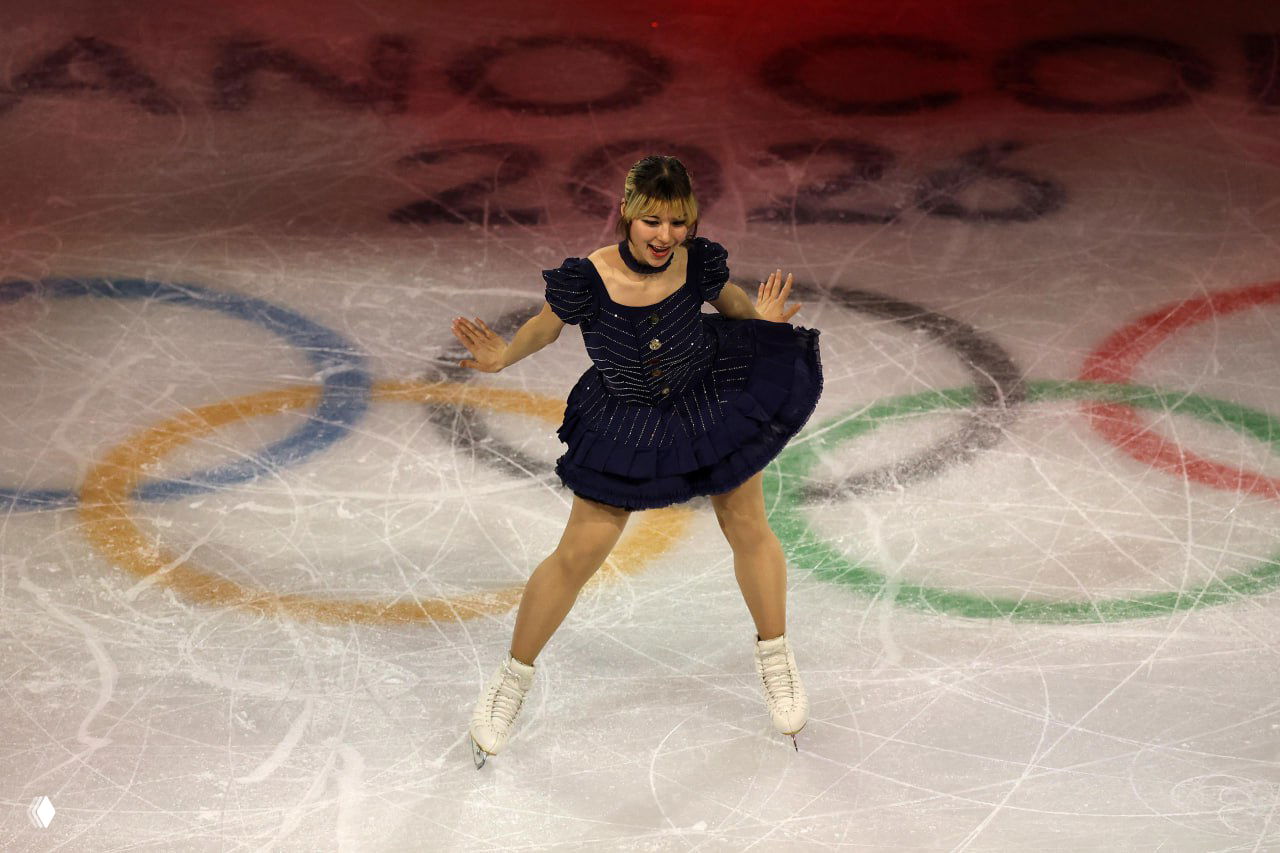 Алиса Лью во время произвольной программы на льду, видны отпечатки коньков и цветные олимпийские кольца на поверхности катка.