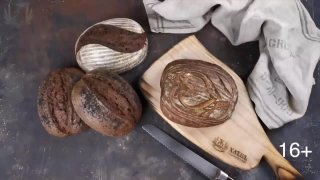 Несколько буханок домашнего хлеба на закваске на деревянной разделочной доске рядом с ножом и льняной тканью, демонстрация результата курса
