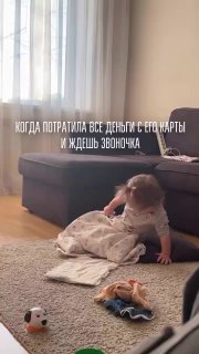 Ребёнок на полу у дивана рядом с игрушками; на видео наложена шутливая надпись про потраченные с его карты деньги.
