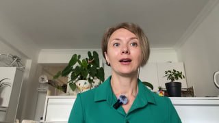 Юлия Краева в домашней обстановке объясняет курс RESET о расслаблении челюсти; женщина смотрит в камеру, на одежде петличный микрофон.
