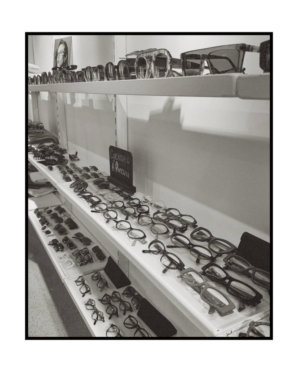 Черно‑белая фотография витрины O.D.L.: несколько полок с очковыми оправами разной формы, акцент на плотной выкладке и дизайне моделей.