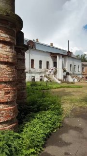 Фасад исторической усадьбы Всеволожских-Оболенских с кирпичным столбом на переднем плане, зеленью и гостями у входа — кадр с фестиваля «Цветы в усадьбе».